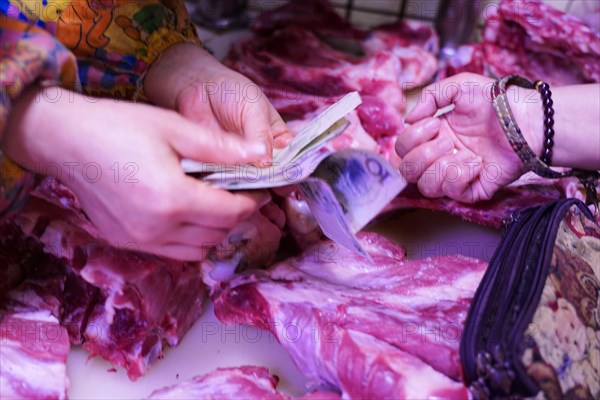 Chongqing, Chongqing Province, China, Two people exchange money for meat at a colourful marketplace, Chongqing, Chongqing Province, China, Asia