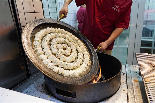 Stroll in Chongqing, Chongqing Province, China, Asia, A cook prepares dumplings in a large pan over an open flame, Chongqing, Asia