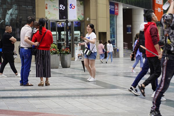 Chongqing, Chongqing Province, China, Asia, People interacting with each other in front of a shopping centre in a busy urban area, Asia