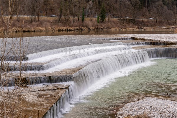 Stepped waterfall flows into a calm river in a wooded landscape, Bad Reichenhall, Bavaria, Germany, Europe