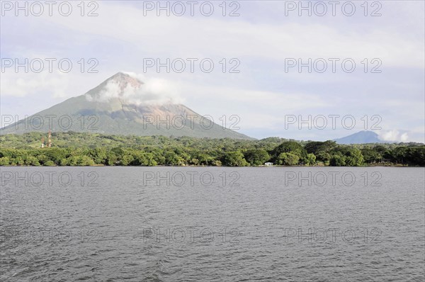 Lake Nicaragua, Ometepe Island in the background, Calm lake with a view of a smoking volcano, surrounded by green vegetation and a cloudy sky, Nicaragua, Central America, Central America