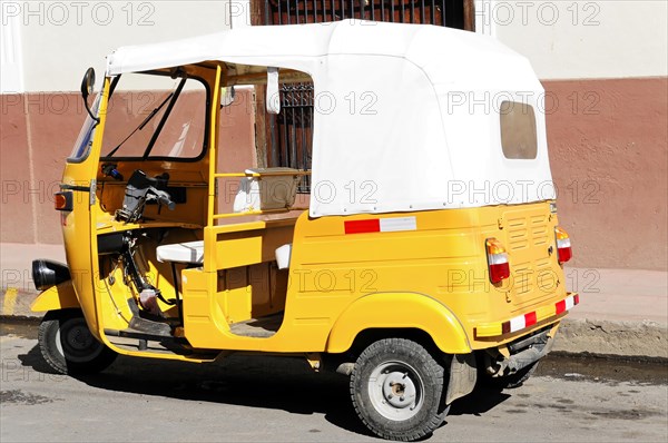 Leon, Nicaragua, Yellow motorbike taxi (Tuc Tuc) parked in front of a white wall, Central America, Central America