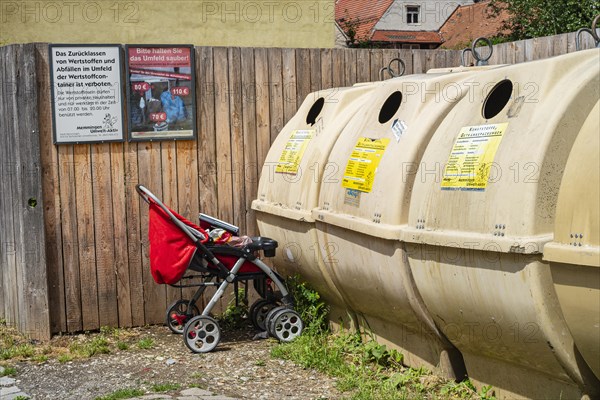 Pushchair left in front of a recycling container in the old town centre of Memmingen, Swabia, Bavaria, Germany, Europe
