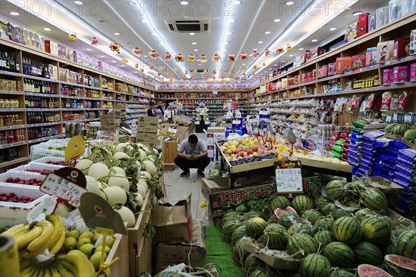 Shanghai, China, Asia, A person sits in the middle of a richly stocked fruit and vegetable shop, People's Republic of China, Asia