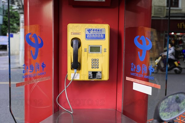 Shanghai, China, Asia, Red public telephone box with Chinese characters and reflections in glass, People's Republic of China, Asia