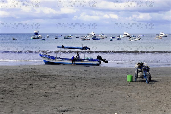 San Juan del Sur, Nicaragua, A fisherman on the beach prepares his boat, a bicycle stands in the sand, Central America, Central America
