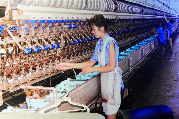 Silk factory Shanghai, A worker operates weaving machines with bobbins of silk threads, Shanghai, China, Asia