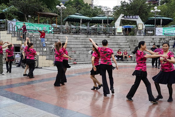A group of people in uniform costumes dancing together in a public square, Chongqing, Chongqing, Chongqing Province, China, Asia