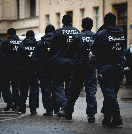 Police officers from a police squad run through the rain, taken during a demonstration in Berlin, 19/04/2024
