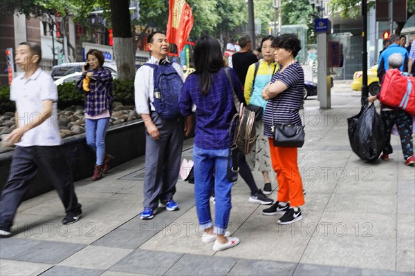 Chongqing, Chongqing Province, China, Asia, Several people stand together in a group and talk on the street, Asia