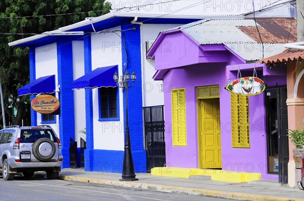 San Juan del Sur, Nicaragua, Cheerful, colourful facades of houses in a street with a parked car in front, Central America, Central America