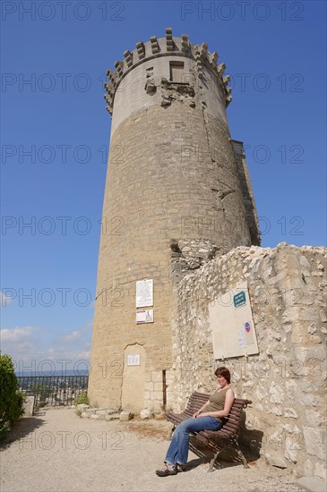 Woman on a bench in front of the castle, Chateaurenard, Bouches-du-Rhone, Provence-Alpes-Cote d'Azur, South of France, France, Europe