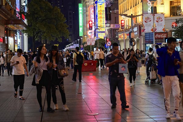 Evening stroll through Shanghai to the sights, Shanghai, People stroll through an illuminated street at night, surrounded by urban scenery, Shanghai, People's Republic of China