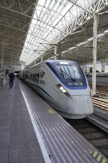 Fast trains, CRH on the platform, Hongqiao railway station, Shanghai, China, Asia. Travellers walk along a train on a platform in a large station concourse, Yichang, Hubei Province, Asia