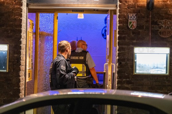 A customs officer enters an illuminated business premises in the evening hours, The Cologne police led a raid against illegal gambling on Friday evening. Around 200 investigators from the police, customs, tax investigation, the public order office, the tax and revenue office, the foreigners authority and the public catering office were out and about on the streets of Cologne on Friday evening. They search 25 properties where there are indications that illegal gambling is taking place. And they make a find