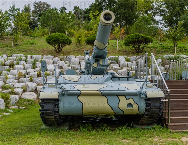 Closeup of military tank with camouflage paint next to wooden stairway in public park in Nonsan, South Korea, Asia