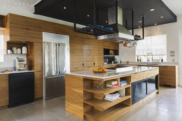 Kitchen with American walnut wood island, cabinets and quartzite countertops inside modern cube style home, Quebec, Canada, North America
