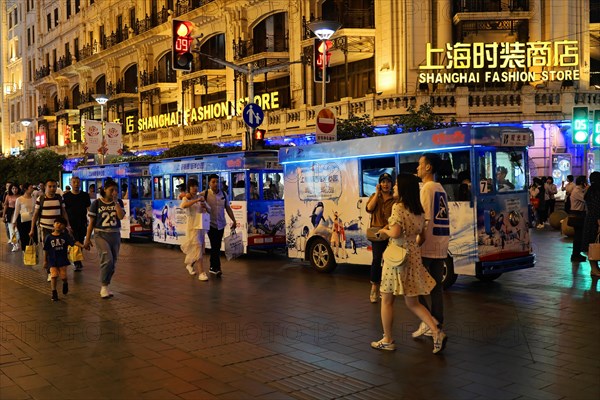Evening stroll through Shanghai to the sights, Shanghai, Lively shopping street at night with a brightly lit bus and passers-by, Shanghai, People's Republic of China