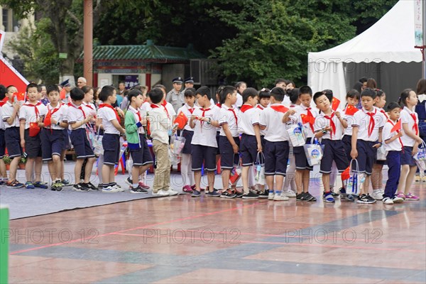 A group of schoolchildren in uniforms with red scarves stand in order on a sports field, Chongqing, Chongqing, Chongqing Province, China, Asia
