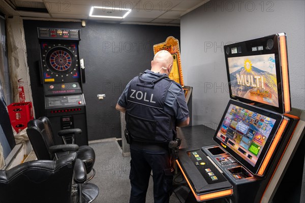 A customs officer checks a slot machine in a dark room, The Cologne police led a raid against illegal gambling on Friday evening. Around 200 investigators from the police, customs, tax investigation, the public order office, the tax and revenue office, the foreigners authority and the public catering office are on the streets of Cologne on Friday evening. They search 25 properties where there are indications that illegal gambling is taking place. And they make a find