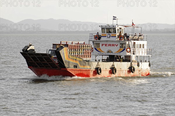 Lake Nicaragua, Ometepe Island in the background, ferry leaving a wave track on the lake, with visible exhaust fumes, under a cloudy sky, Nicaragua, Central America, Central America