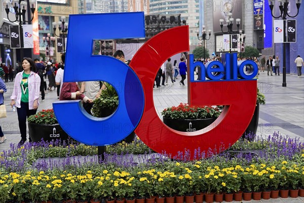 Strolling in Chongqing, Chongqing Province, China, Asia, Advertisement for 5G technology in an urban garden area surrounded by passers-by, Chongqing, Asia