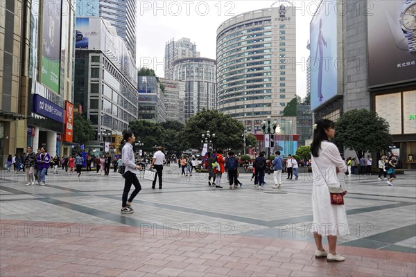 Chongqing, Chongqing Province, China, Asia, People walking across a square in front of modern buildings and skyscrapers, Asia