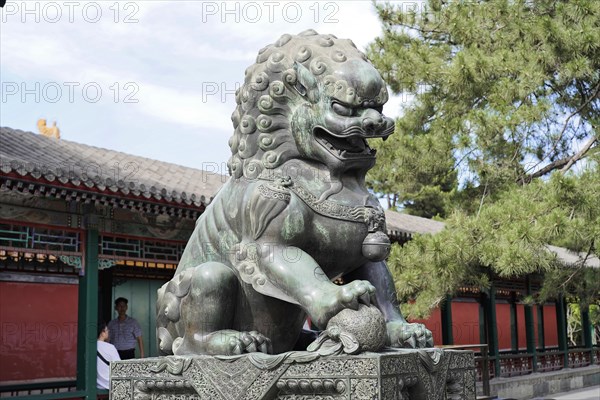 New Summer Palace, Beijing, China, Asia, Statue of a Chinese stone lion in front of traditional architecture and blue sky, Beijing, Asia
