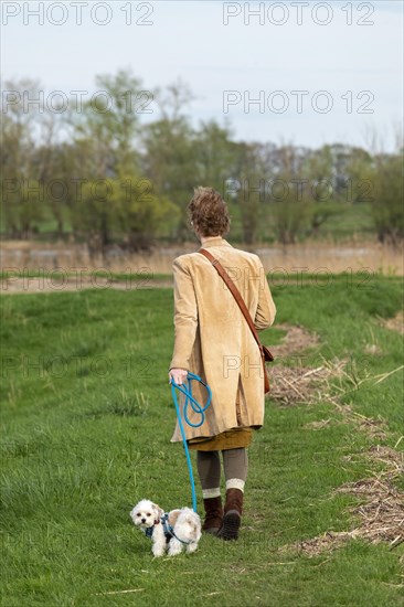 Woman walking Bolonka Zwetna dog, Elbtalaue near Bleckede, Lower Saxony, Germany, Europe