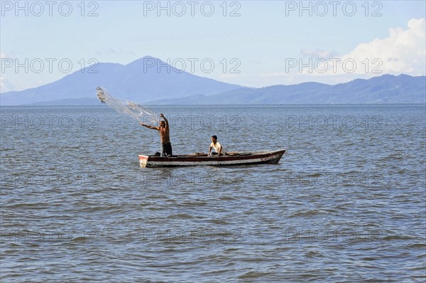 Lake Nicaragua, Two men in a boat casting a fishing net on a lake, mountains in the background, Nicaragua, Central America, Central America