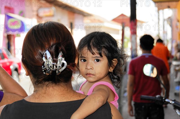 Leon, Nicaragua, A child looks over the shoulder of a woman in a busy city street, Central America, Central America