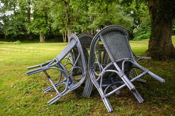 Four chairs are grouped around a table under a tree in a park, St George's Monastery, Isny im Allgaeu, Baden-Wuerttemberg, Germany, Europe