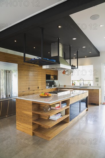 Kitchen with American walnut wood island, cabinets and quartzite countertops inside modern cube style home, Quebec, Canada, North America