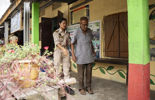 BOKAKHAT, INDIA, APRIL 19: A security personnel helps an elderly person at a polling station during the first phase of the India's general elections on April 19, 2024 in Bokakhat, Assam, India. Nearly a billion Indians vote to elect a new government in six-week-long parliamentary polls starting today