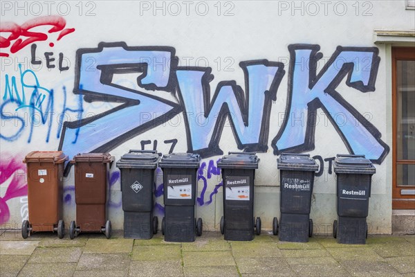 Rubbish bins in front of a graffiti-covered house wall, Bremen, Germany, Europe
