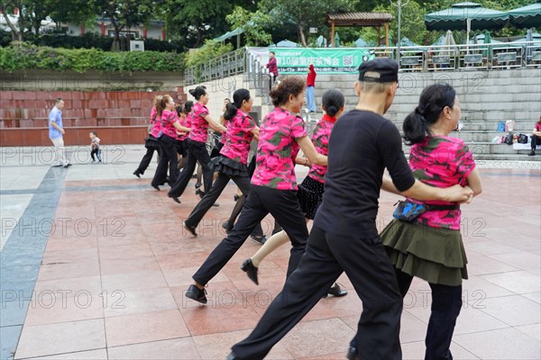 Residents of Chongqing dancing in the city centre, Chongqing, China, Asia, Several couples practice street dance, dressed in black and pink, on a paved surface, Chongqing province, Asia