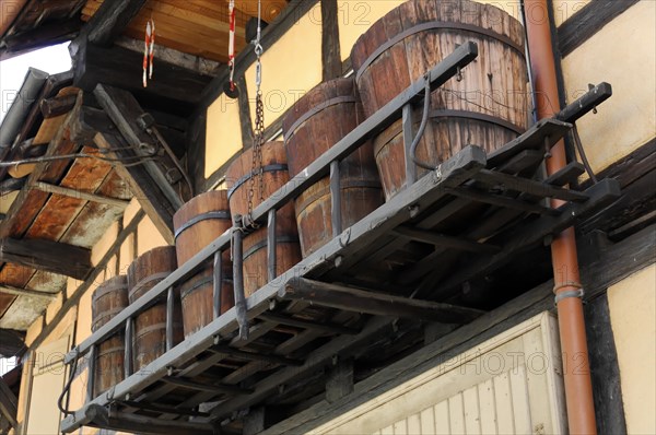 Eguisheim, Alsace, France, Europe, Wooden barrels stored on a beam on the outside of a half-timbered house, Europe