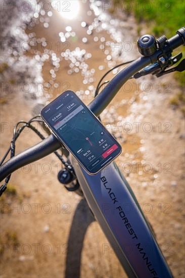 View over the handlebars of an e-bike with display and smartphone in sunlight, spring, e-bike forest bike, Gechingen, Black Forest, Germany, Europe