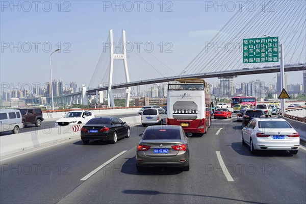 Traffic in Shanghai, Shanghai Shi, Heavy traffic on a motorway with a large bridge in the background, Shanghai, People's Republic of China