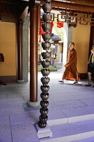 Jade Buddha Temple, Shanghai, Monk walking past ornate temple pillars and traditional carvings, Shanghai, China, Asia