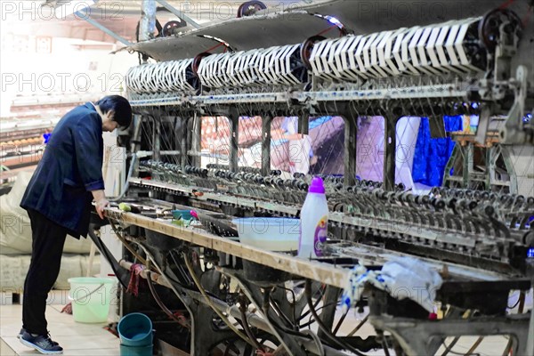 Silk factory Shanghai, A worker cleans and maintains a machine in a textile factory, Shanghai, China, Asia