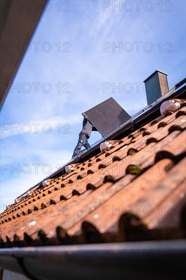 A labourer works on a tiled roof, solar systems construction, craft, Muehlacker, Enzkreis, Germany, Europe