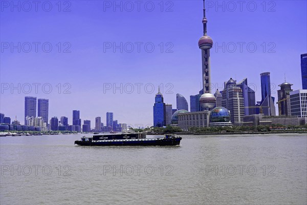 Stroll through Shanghai to the sights, Shanghai, China, Asia, A cargo ship sails on the river in front of the Shanghai skyline, Asia