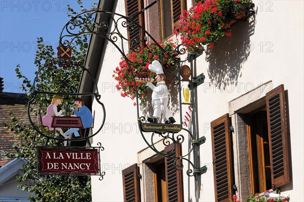 Eguisheim, Alsace, France, Europe, An elaborate pub sign shows a chef with guests, Europe