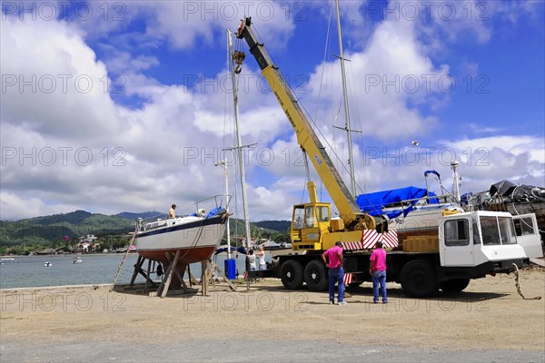 San Juan del Sur, Nicaragua, A crane lifts a boat in the harbour, Workers watch the operation, Central America, Central America