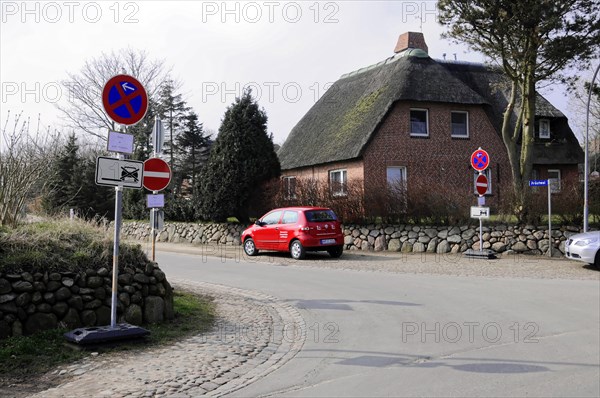 Sylt, North Frisian Island, Schleswig Holstein, Street corner with traffic sign next to a thatched roof house and a parked car, Sylt, North Frisian Island, Schleswig Holstein, Germany, Europe