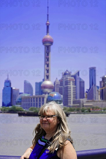 Stroll through Shanghai to the sights, Shanghai, China, Asia, A woman smiles with the skyline of Shanghai with Oriental Pearl Tower in the background, Asia