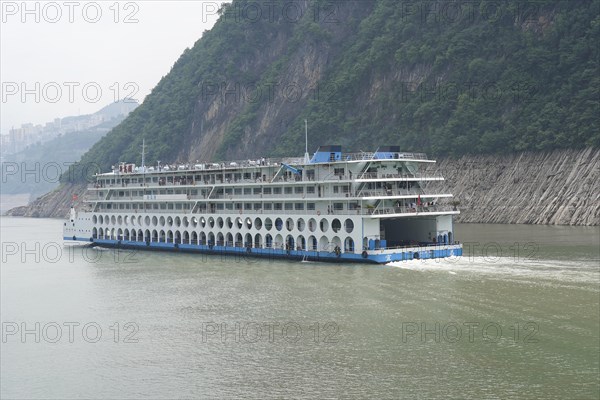 Chongqing, Chongqing Province, Cruise ship on the Yangtze River, A white and blue river cruise ship on calm waters in front of forested hills, Chongqing, Chongqing Province, China, Asia