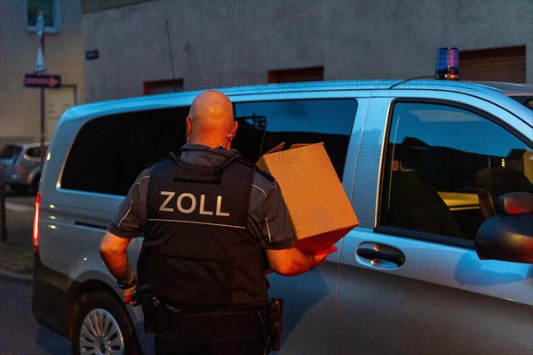 A customs officer carries a cardboard box to an official vehicle in the evening, The Cologne police led a raid against illegal gambling on Friday evening. Around 200 investigators from the police, customs, tax investigation department, public order office, tax and revenue office, immigration office and gas office are on the streets of Cologne on Friday evening. They search 25 properties where there are indications that illegal gambling is taking place. And they make a find