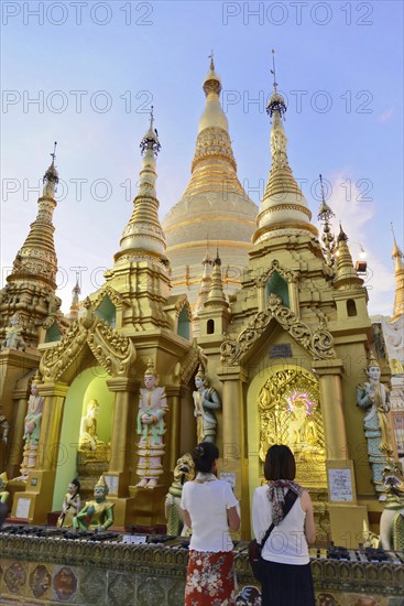 Shwedagon Pagoda, Yangon, Myanmar, Asia, Visitors marvel at the glowing golden spires of the Shwedagon Pagoda as dusk falls, Asia